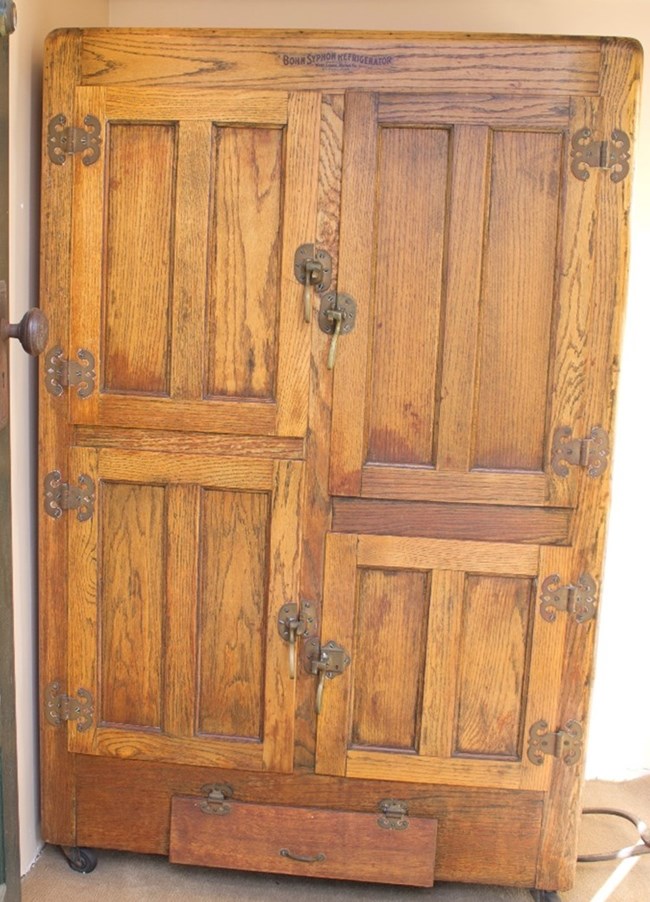 A light brown wooden icebox with four compartments