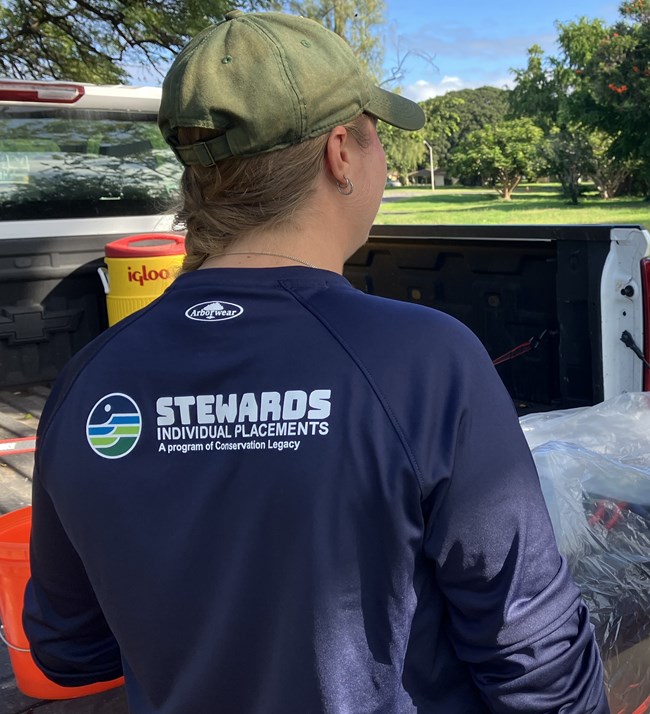 Woman in ball cap wears shirt that reads "Stewards Individual Placements, a program of Conservation Legacy"