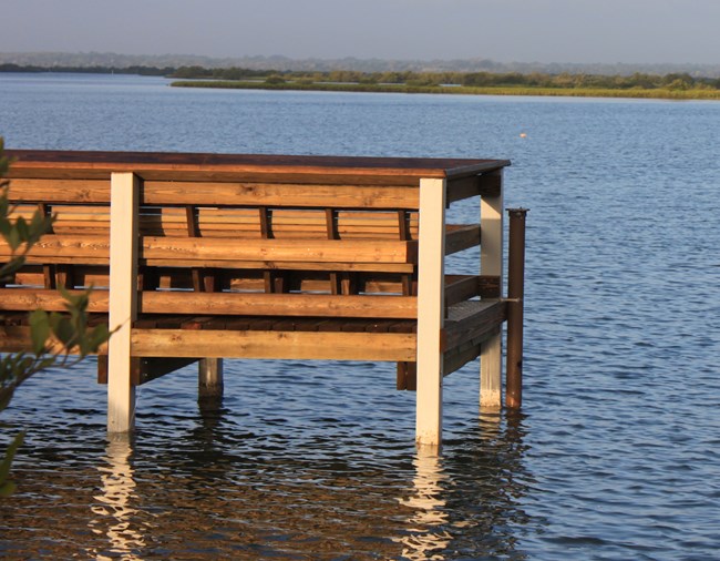 Dock at the edge of water with a pvc pipe attached.