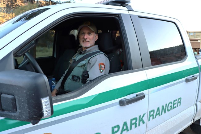 A law enforcement ranger smiles at us from his patrol vehicle.