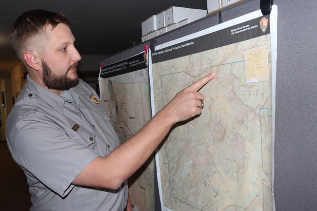 A park planner points at a map of Valles Caldera National Preserve.
