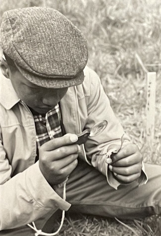 Child sitting on the ground studies a leaf