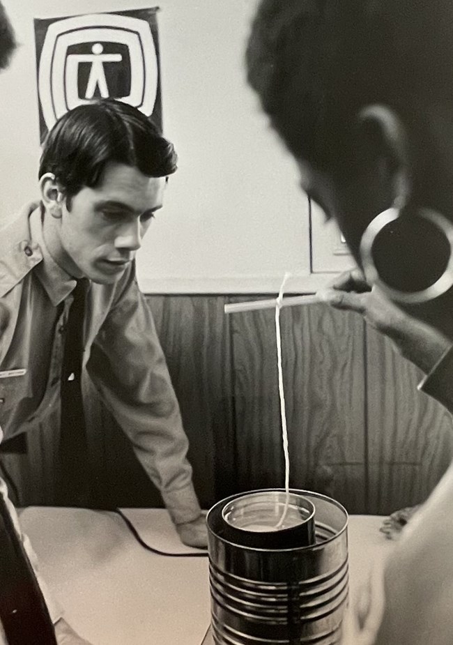 A ranger watches as a child makes a candle