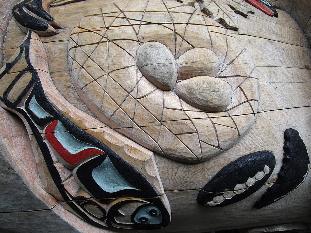 A section of a totem pole carving showing gull eggs in a nest.