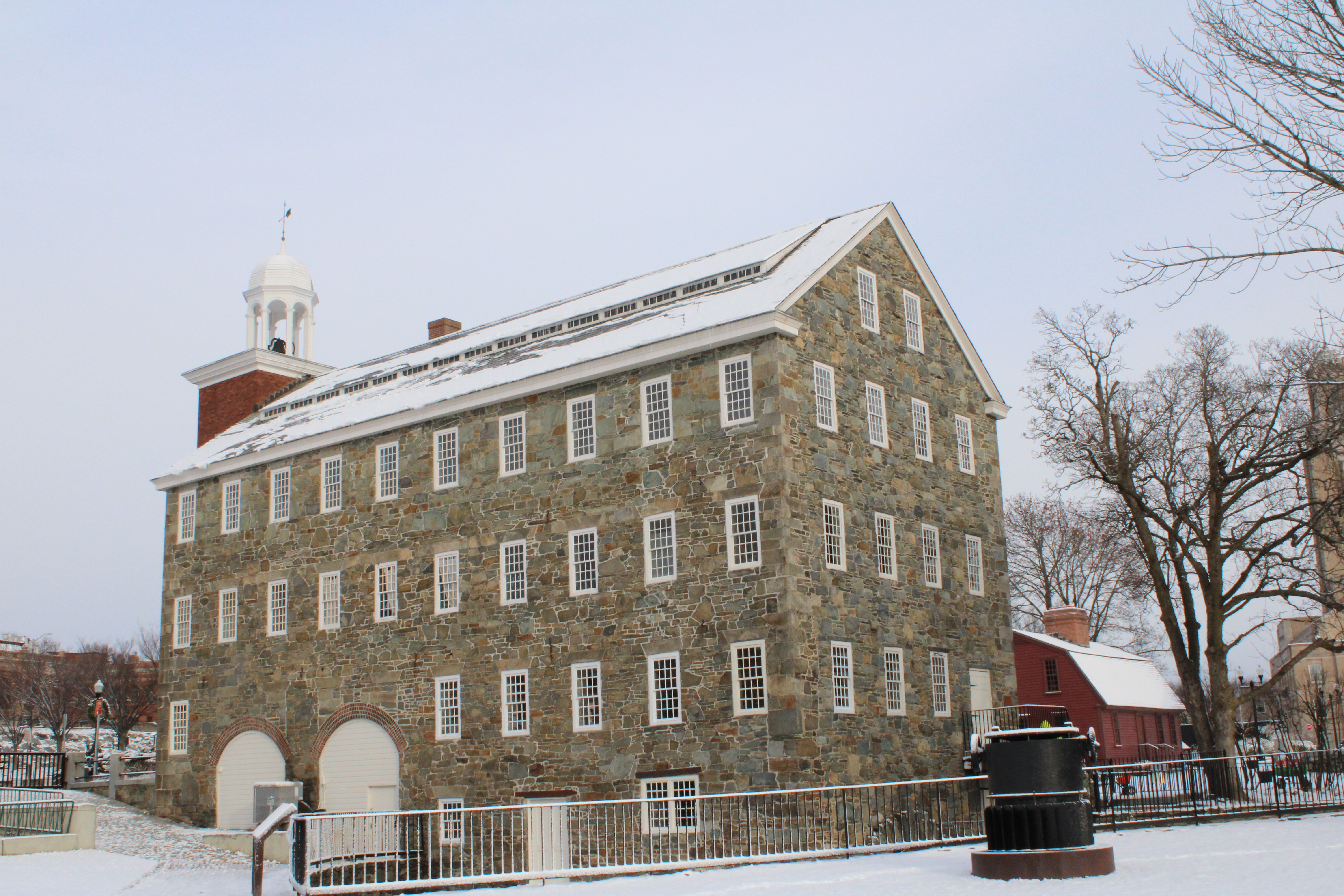Four-story stone building with window and brick tower with cupola at far left