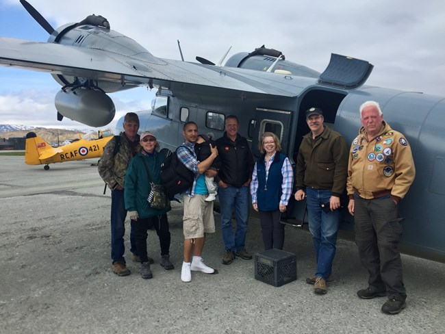 Group of people standing in front of World War II restored plane.