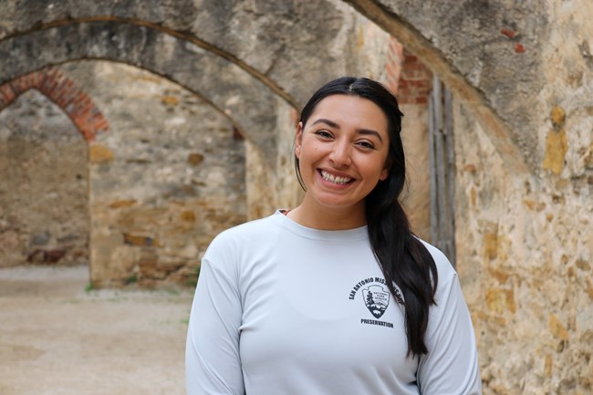 Woman standing smiling under stone arches