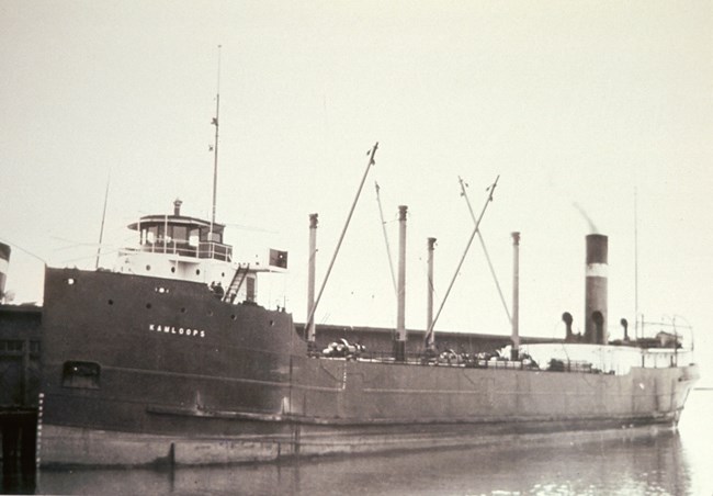 black and white photo of the SS Kamloops docked with a substantial box-like building either on the dock of behind it, hidden by the ship