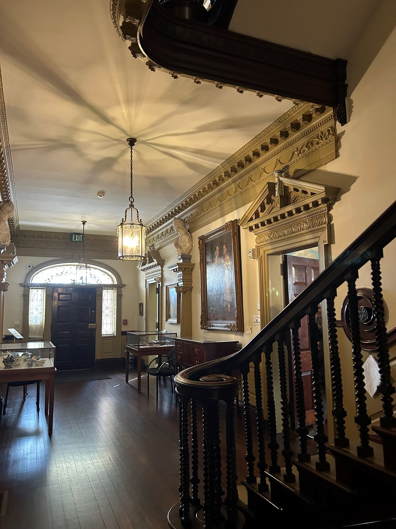 Hallway inside of colonial area house with stairway banister in the foreground