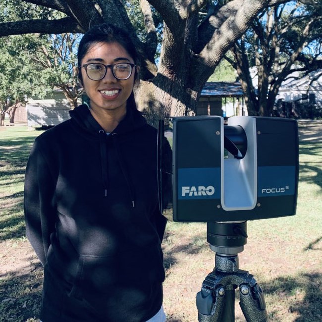 A woman stands next to a 3D scanner