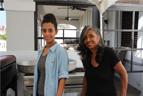 Two women stand smiling in a makeshift kitchen.