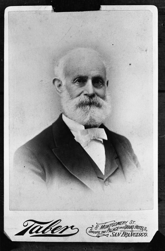 A portrait photograph of a man with a bushy white beard.