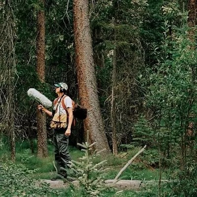 Man stands in forest with sound research equipment