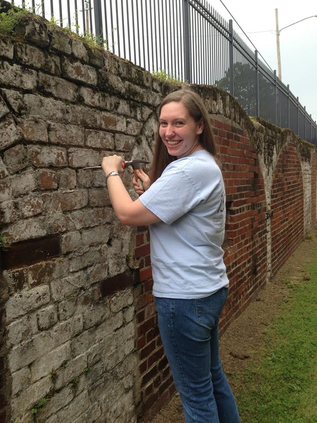 Jamie Dail (MFA, Historic Preservation 2015) removes failed mortar from a historic brick wall.