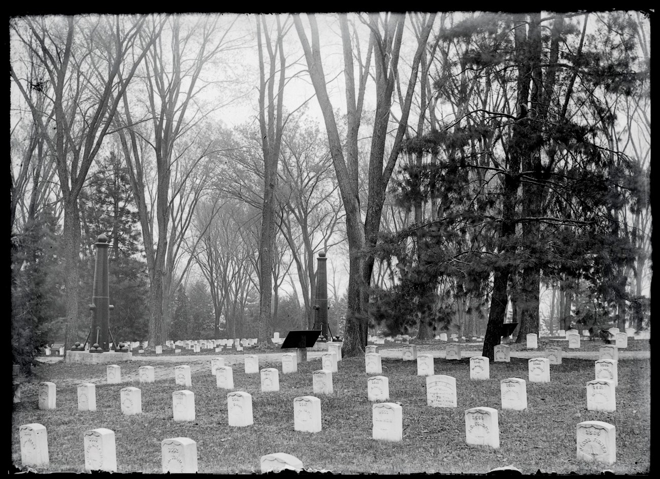 Black and white photo a cemetery with white headstones.