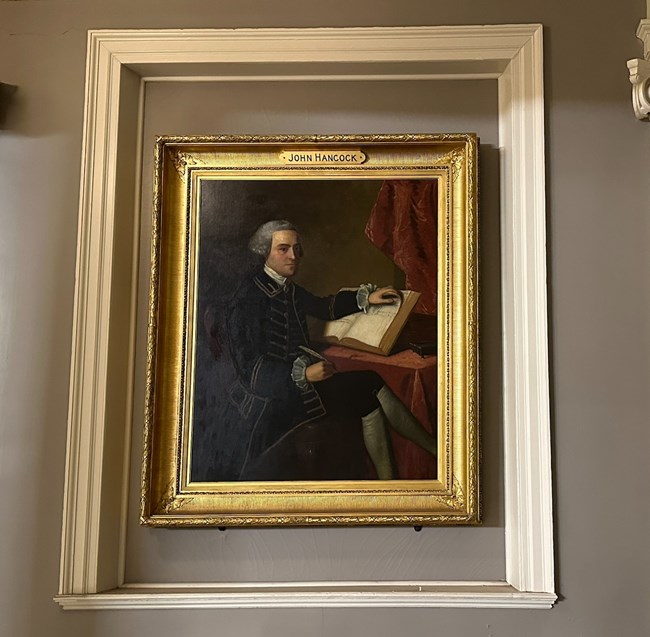 Portrait of John Hancock hanging on a wall with white trim around it.