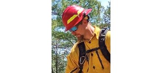 Spaak in a red helmet and yellow shirt, wearing sunglasses. He's actively working and not looking at the camera.