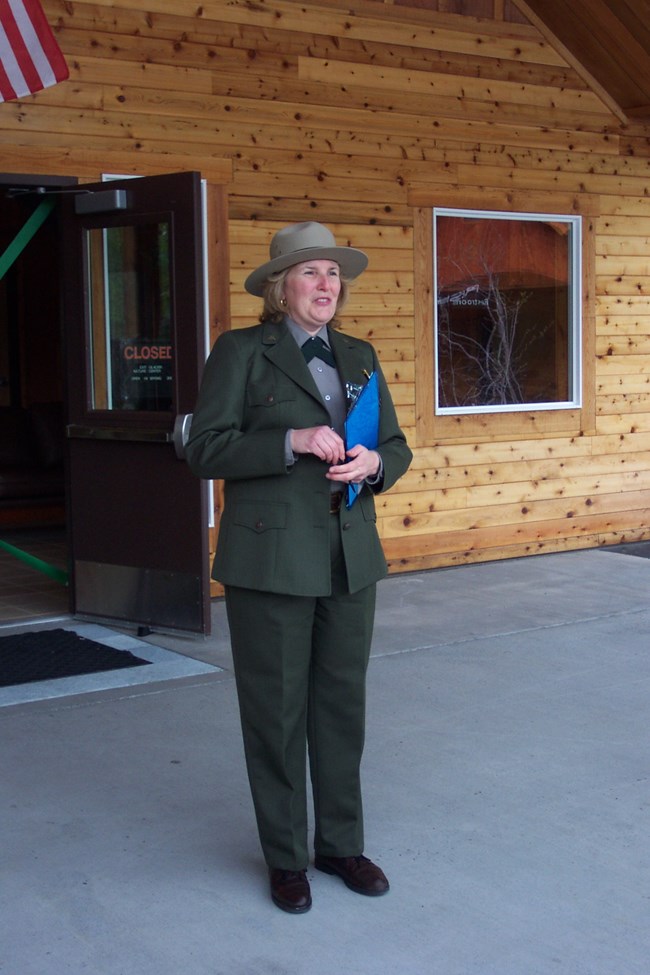 Woman in uniform stands in front of building