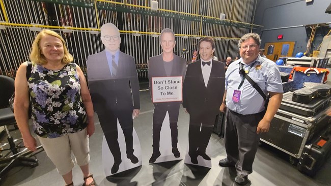 A male and woman pose next to a Steve Martin & Martin Short cutout backstage.