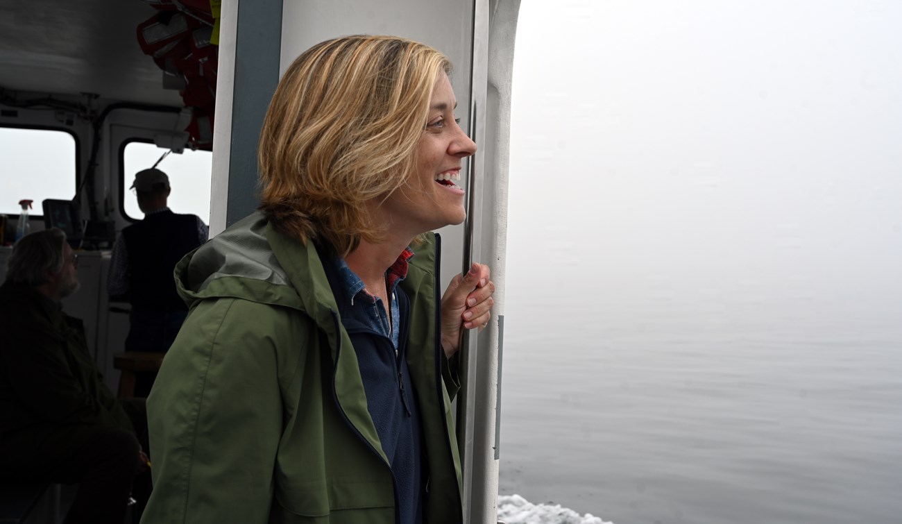 Woman holds a rail standing at the side of a ferry boat in open water