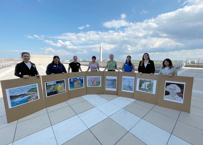 Interns holding pictures of their artworks during a conference at the National Park Service headquarters in Washington, DC.