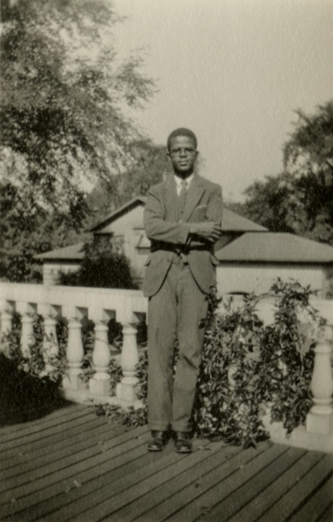 Candid portrait of a Black man standing outside on a porch.