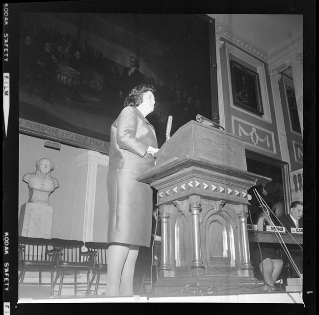 Black and white photo of Louise Day Hicks standing on the stage of Faneuil Hall