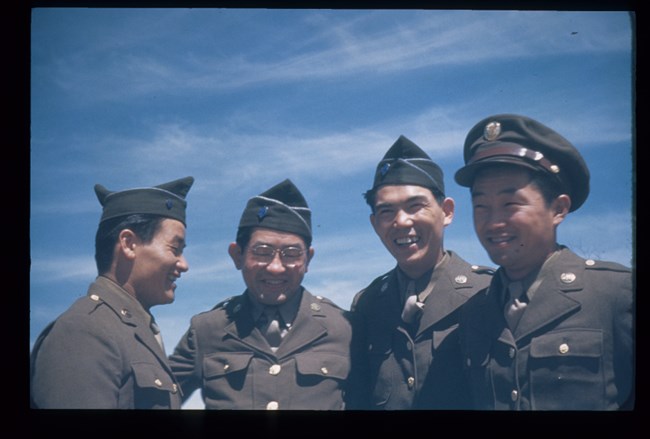 Four men in military uniforms smiling