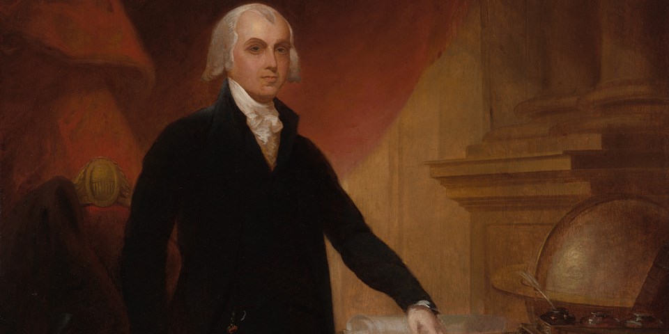 Madison standing in a black coat next to a globe.