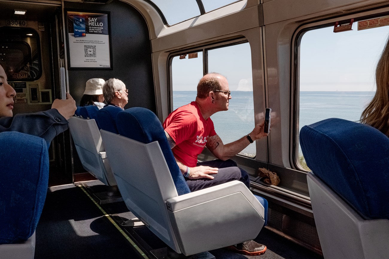 A man sitting in a train, holding a cell phone