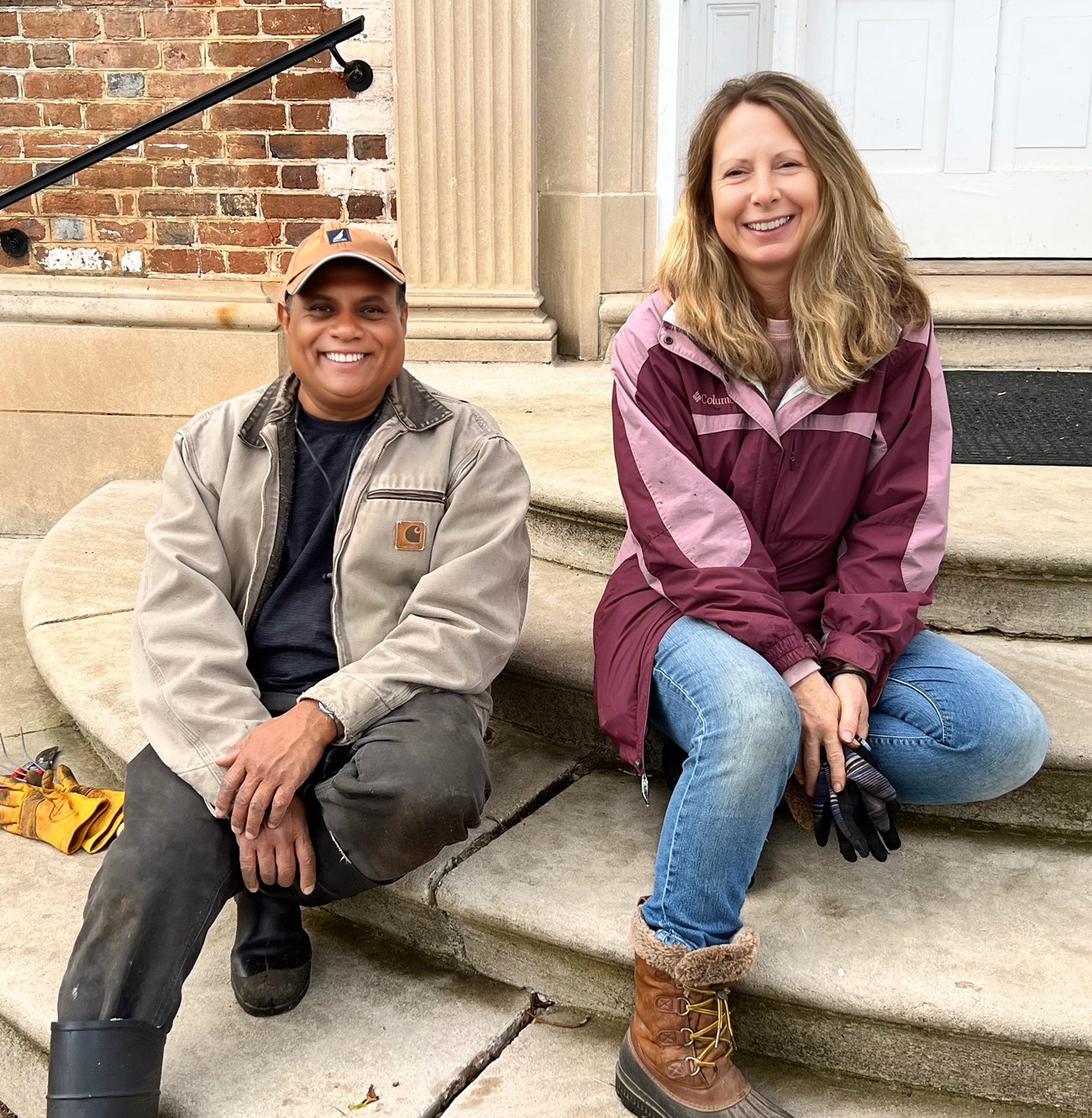 Chatham Garden Club volunteers Mannon and AJ, seated on stairs leading to the garden side entracnh to Chatham Manor.