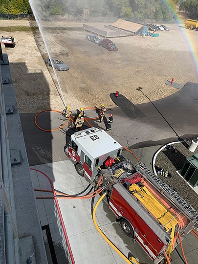 Overhead of a fire engine with structural firefighters aroound a brick building.