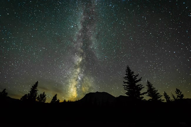 Milky Way stars over a silhouetted mountain.