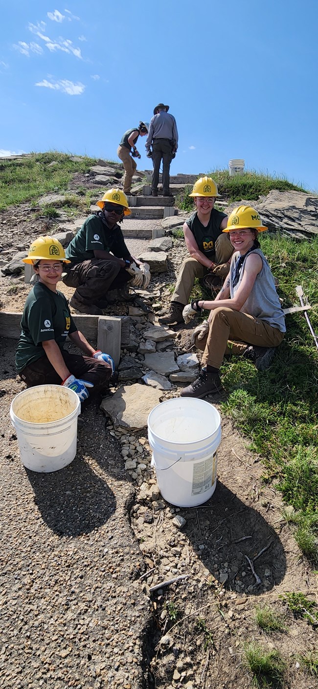 Group of Trail Crew Members sit on the ground along steps while conducting erosion control work.