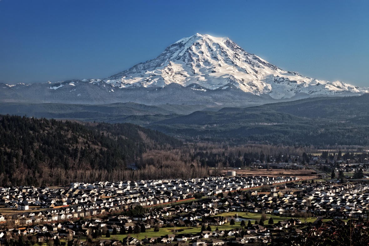 snow covered volcanic peak in the distance and housing in the foreground