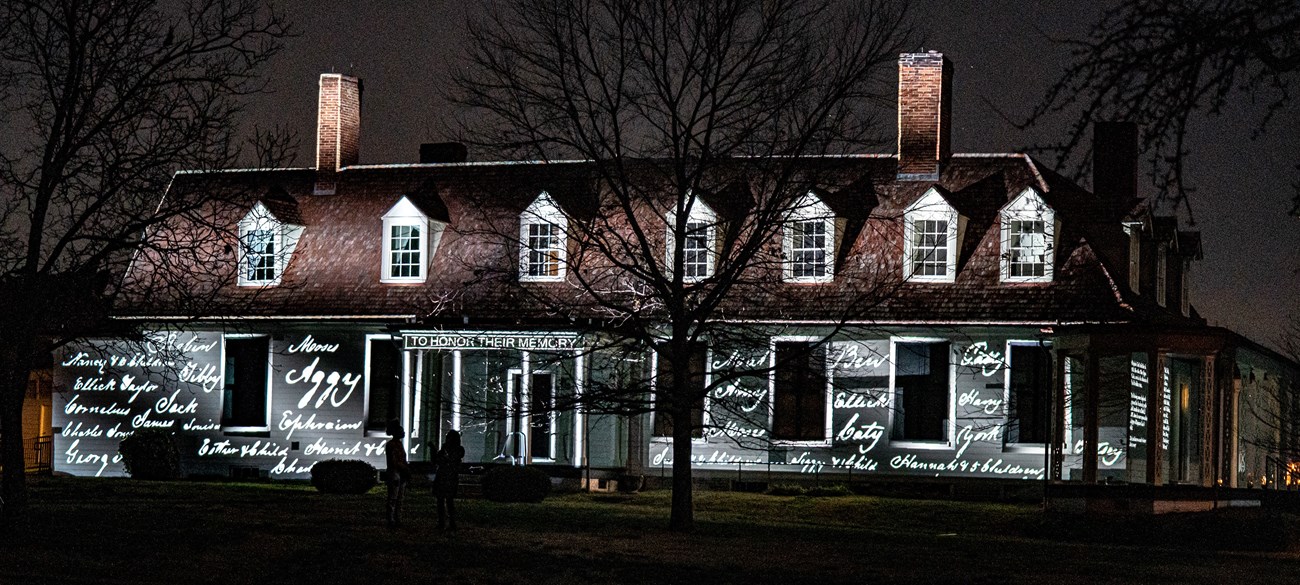 A photo of a home a night with names projected on the siding.