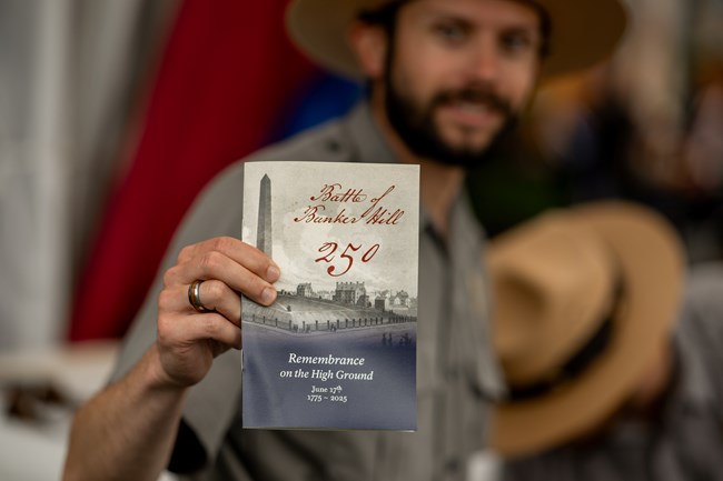 ranger holding a commemorative booklet for the event.