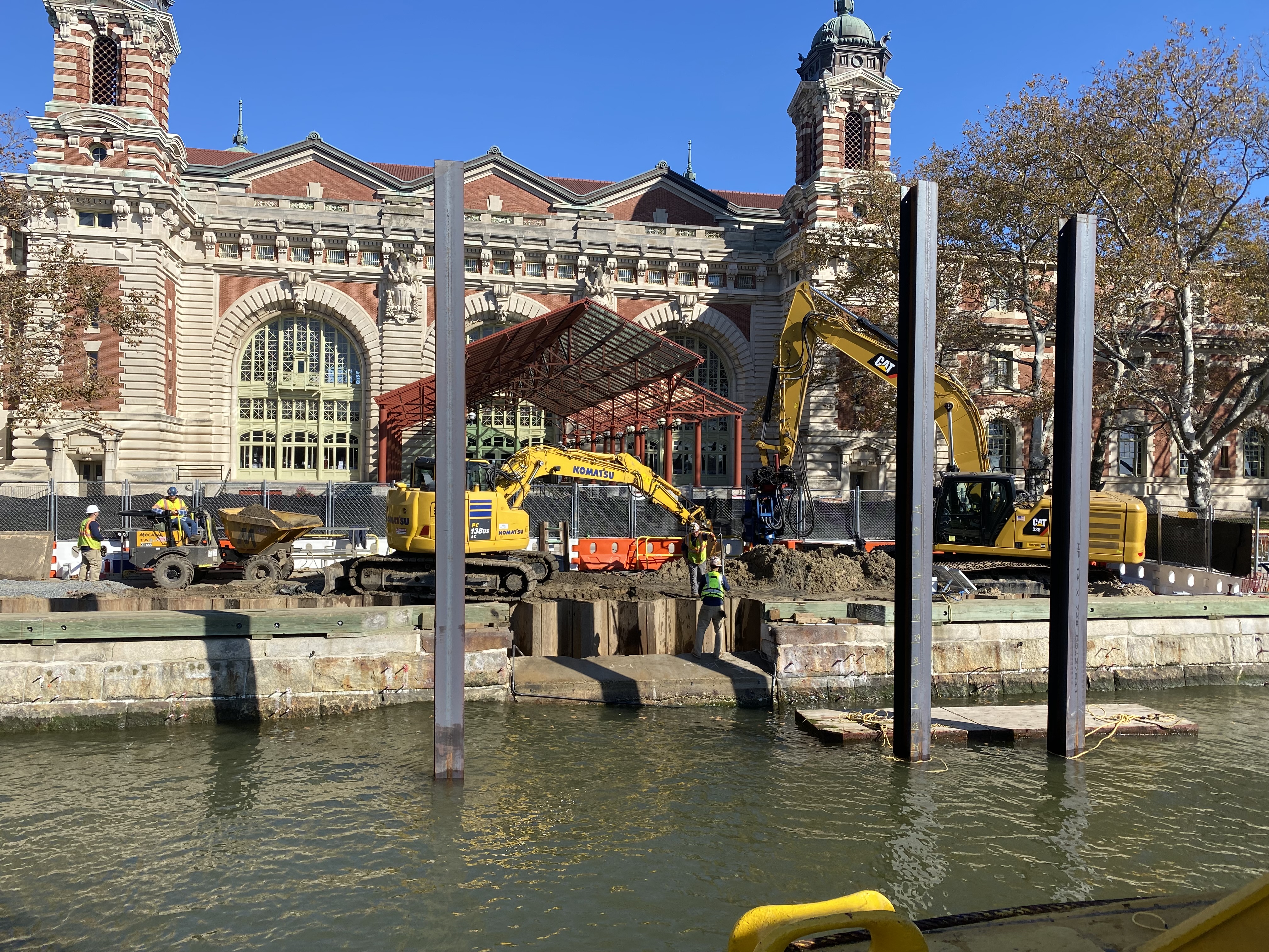 Heavy machinery dig into the ground in front of a large building.