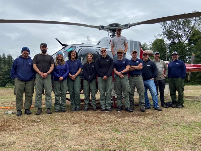 A group of people in front of a helicopter smiles at the camera