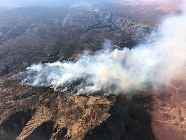 Aerial view of smoke and desert landscape.