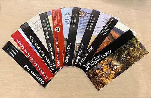 Nine brochures laying on the table in an arch shape.