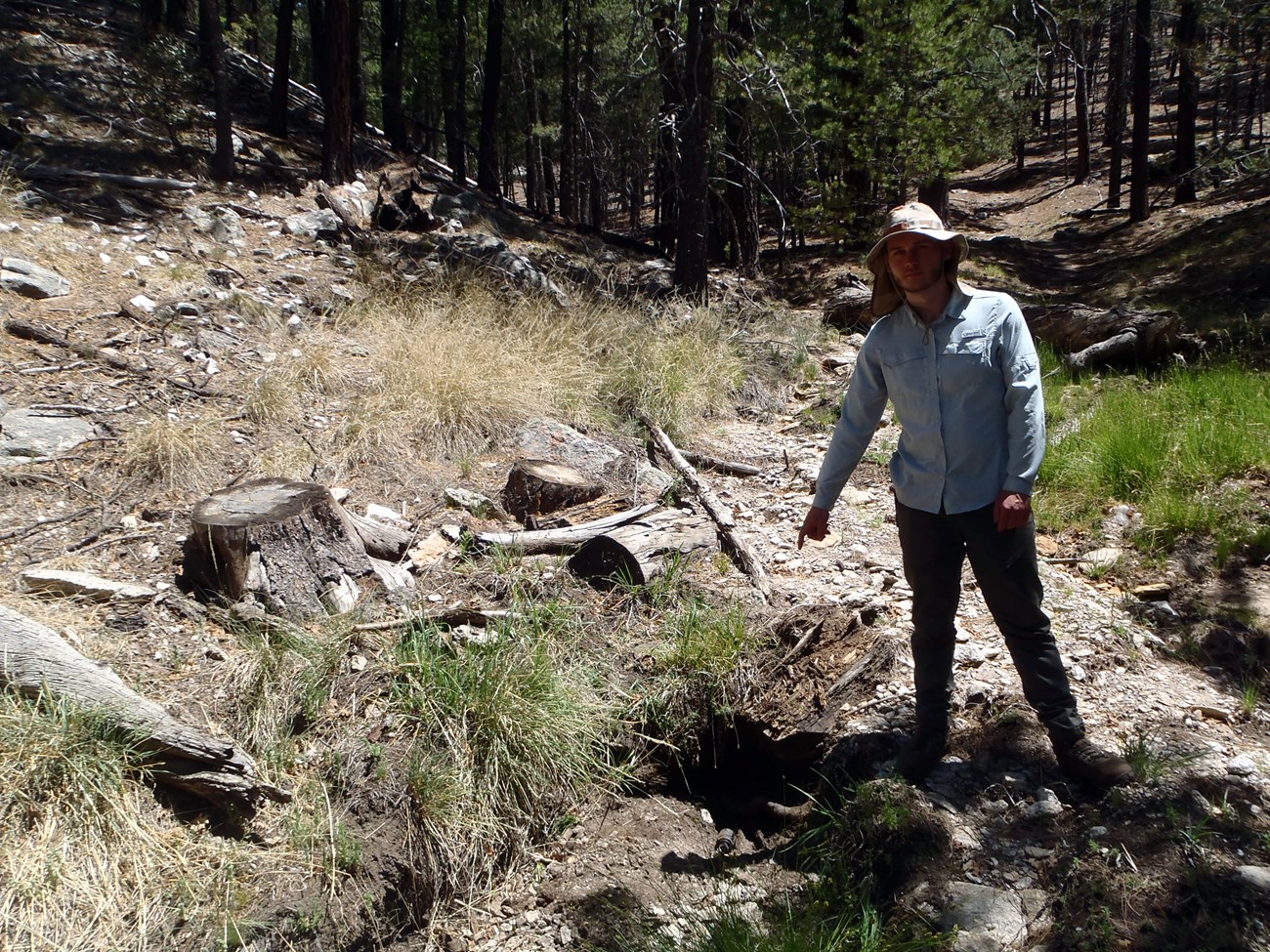 A person pointing at a depression in the ground that is dry.