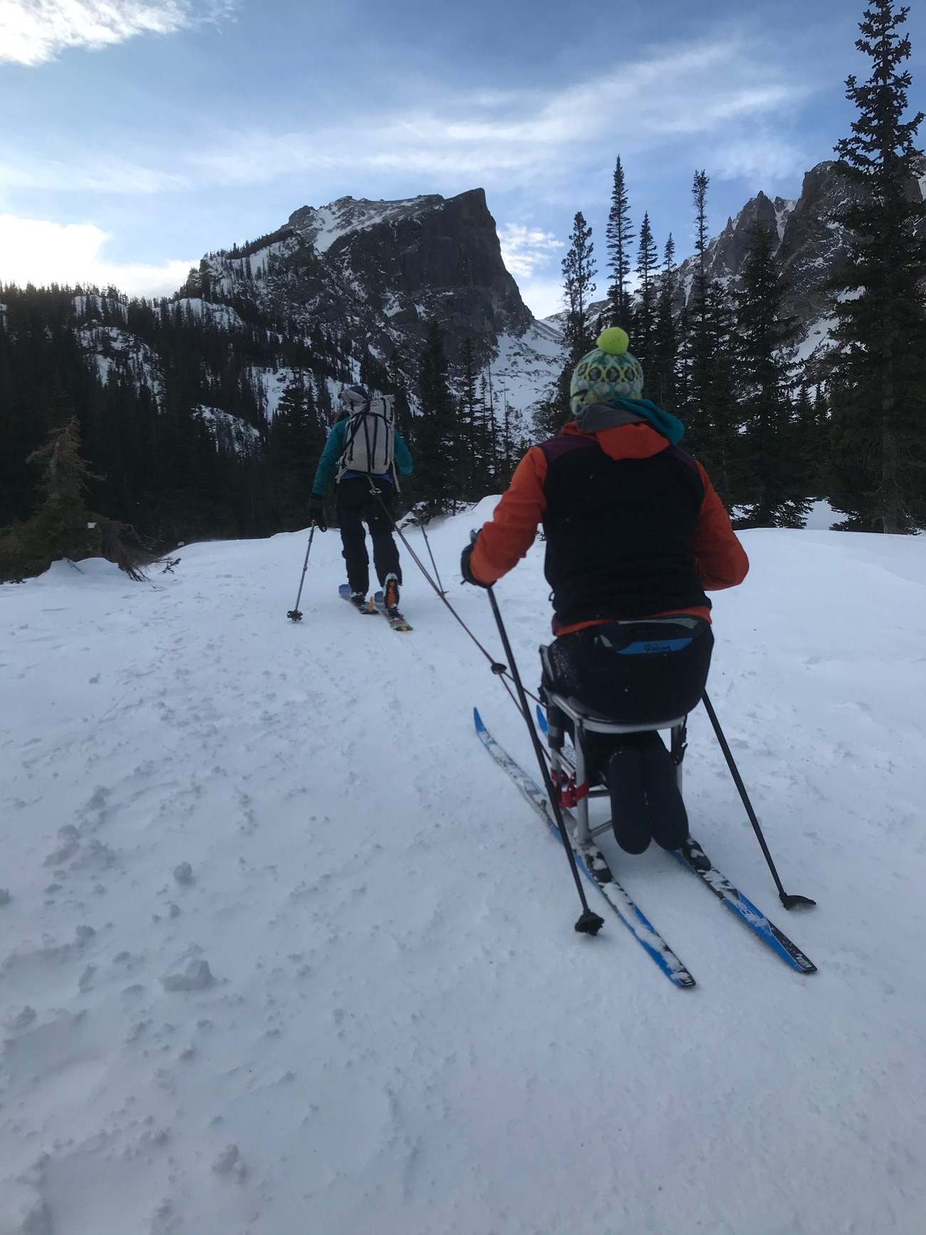 a person uses a set of seated skiis on a snowy trail