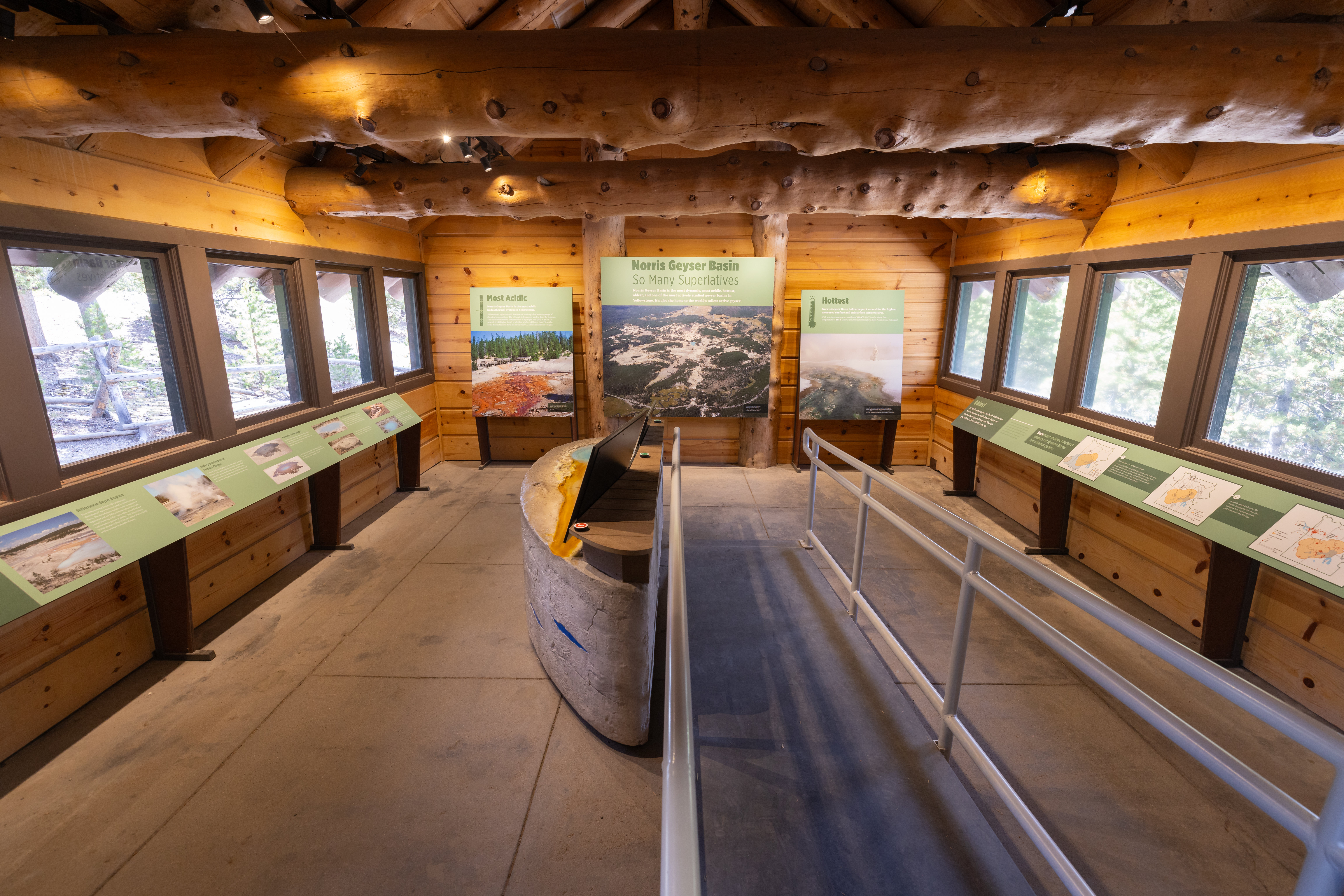 An interior space with exhibits showing photos and text. Wooden floors, walls, and ceiling.