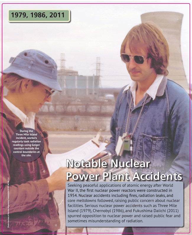 A man and woman standing outside a nuclear power plant cooling tower, holding clipboards.