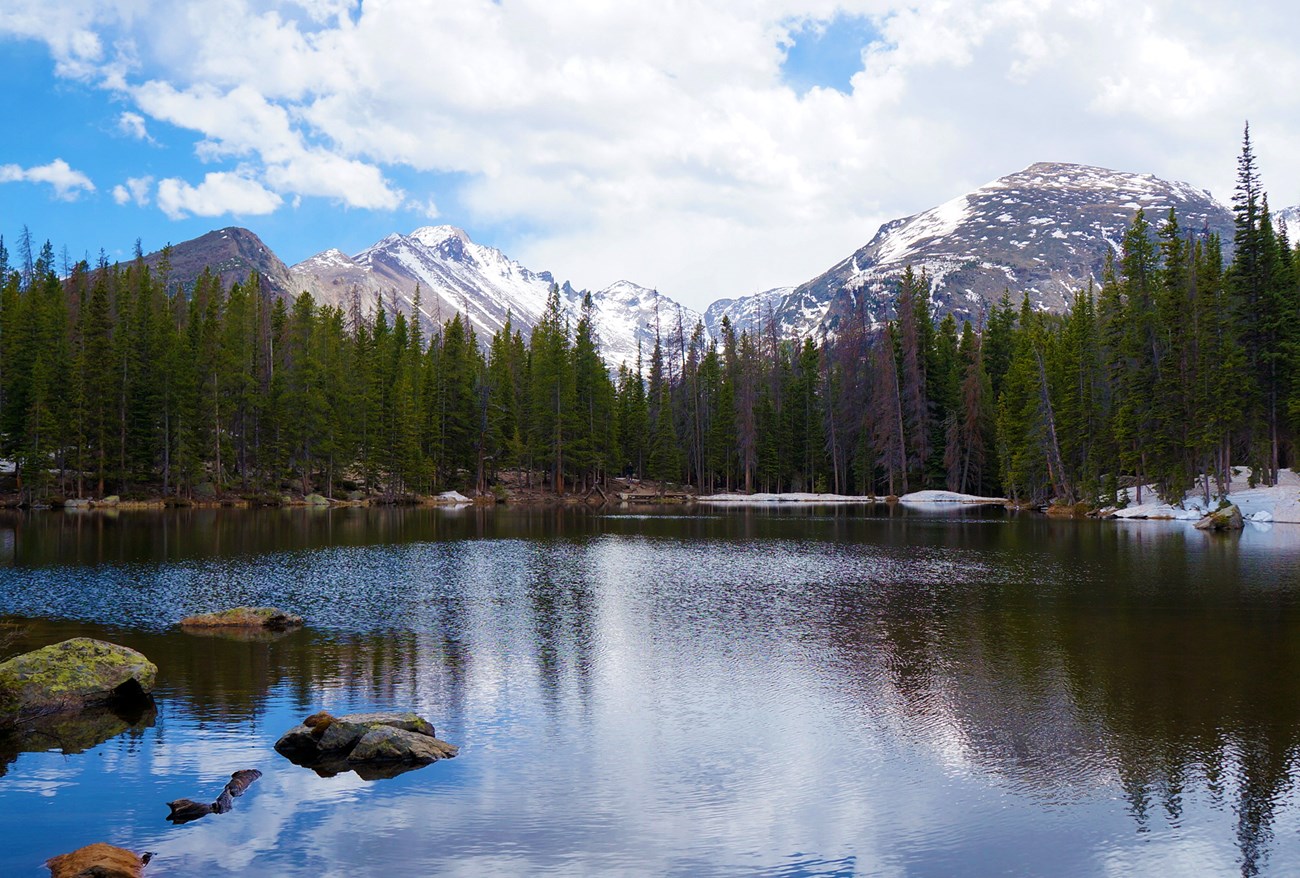 A lake surrounded by snow-capped peaks and evergreen trees.