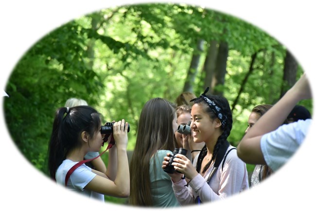 Kids holding binoculars in the woods