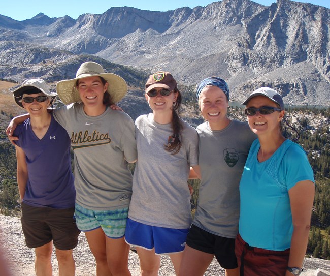Five women pose for group photo with a view of granite mountains behind them.