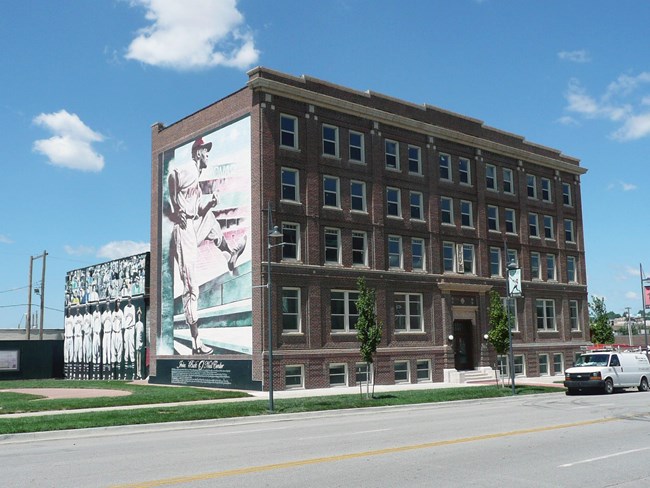 Brick building with mural of baseball players on it.