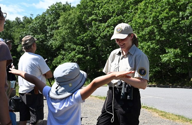 SCA Intern Jazmine shows junior rangers the wingspan of a peregrine falcon compared to their outstretched arms.